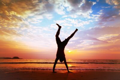 How to use your strengths - person doing a handstand on a beach at sunset.